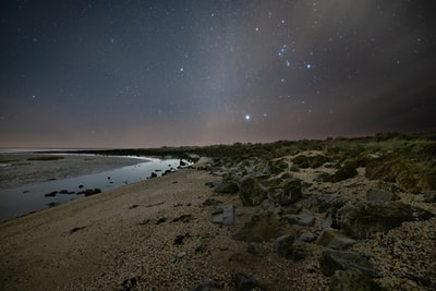褐色的岩石海岸在夜间在蓝色的天空下
